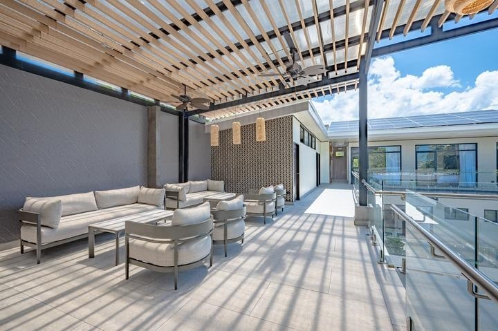 Beachfront Jaco, Costa Rica - Vacation Rental Casa Las Palmas • Costa Rica Elite Sunlit rooftop lounge with white sectional sofas, chairs, and glass railing overlooking a blue sky.