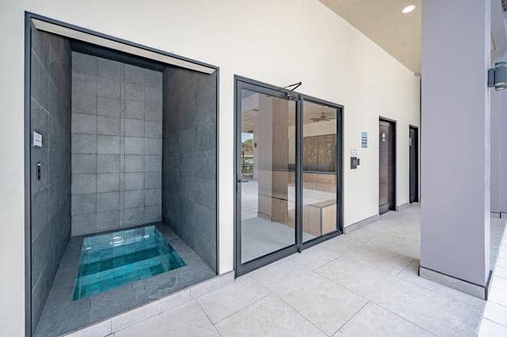 Beachfront Jaco, Costa Rica - Vacation Rental Casa Las Palmas • Costa Rica Elite Indoor corridor with glass sliding doors; a small tiled soaking pool in a stone alcove on the left.